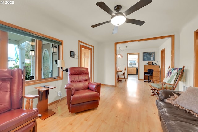 living area with ceiling fan, baseboards, and wood finished floors