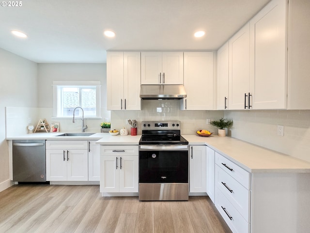 14127 SE Center St, Portland, OR 97236 - kitchen with appliances with stainless steel finishes, under cabinet range hood, light wood-type flooring, backsplash, and recessed lighting