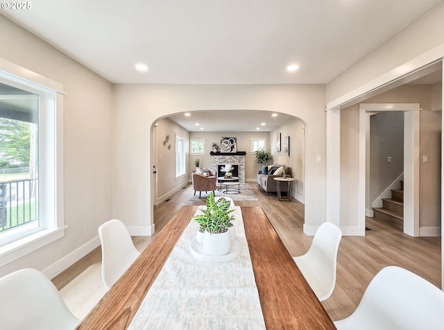 14127 SE Center St, Portland, OR 97236 - dining room with arched walkways, light wood finished floors, a fireplace, recessed lighting, and stairway
