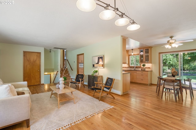living area featuring light wood-style flooring, stairway, and ceiling fan