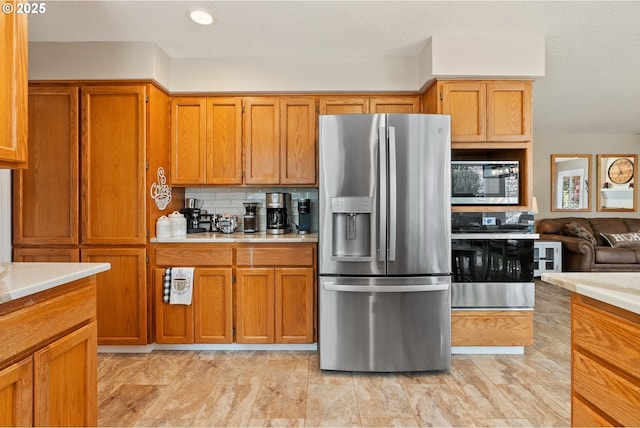 kitchen featuring light countertops, backsplash, brown cabinets, and stainless steel appliances