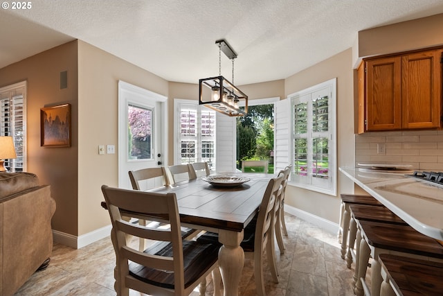 dining space featuring baseboards, visible vents, stone finish floor, and a notable chandelier