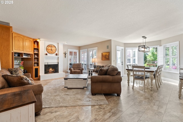 living area featuring visible vents, a textured ceiling, a healthy amount of sunlight, and a fireplace