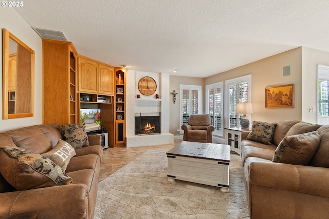 living area with a fireplace, a textured ceiling, and visible vents