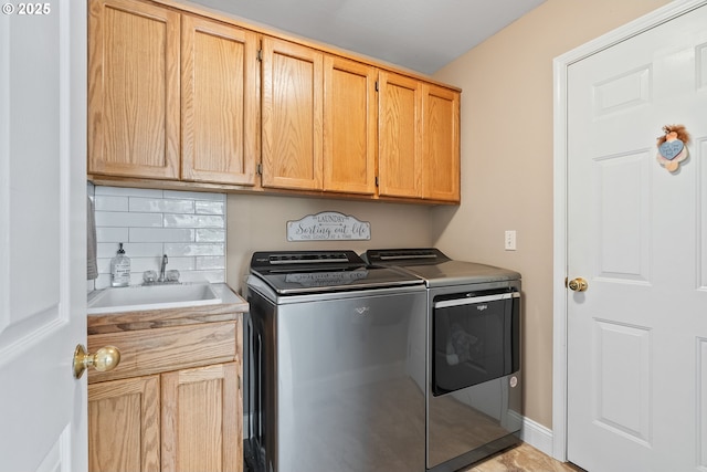 washroom with cabinet space, washing machine and dryer, and a sink