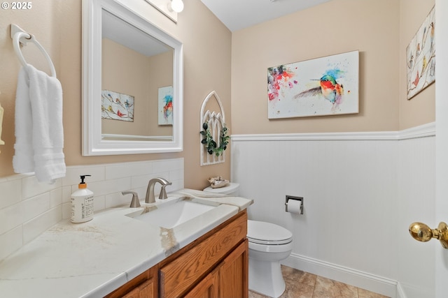 half bathroom with toilet, a wainscoted wall, and vanity