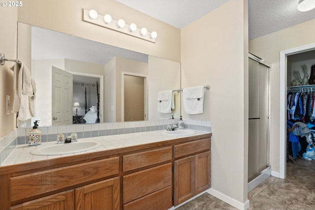 full bathroom with double vanity, a sink, tile patterned flooring, and a shower stall
