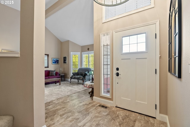 foyer entrance featuring visible vents, baseboards, and high vaulted ceiling