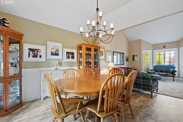dining area featuring a notable chandelier, a wainscoted wall, and vaulted ceiling