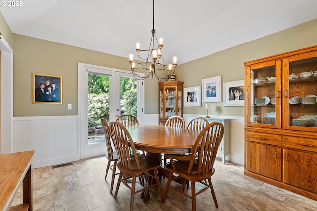 dining room with visible vents, wainscoting, a chandelier, french doors, and vaulted ceiling
