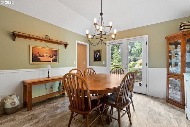 dining room featuring a chandelier, wainscoting, and lofted ceiling