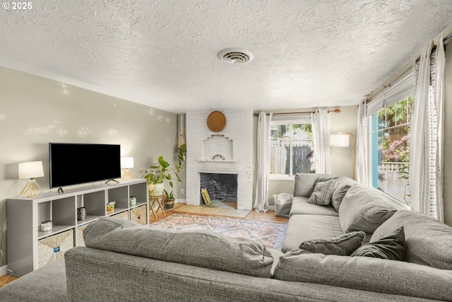 living area featuring a brick fireplace, baseboards, wood finished floors, and a textured ceiling