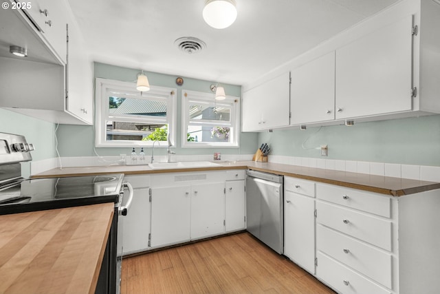 kitchen with appliances with stainless steel finishes, white cabinets, light wood-style flooring, and a sink