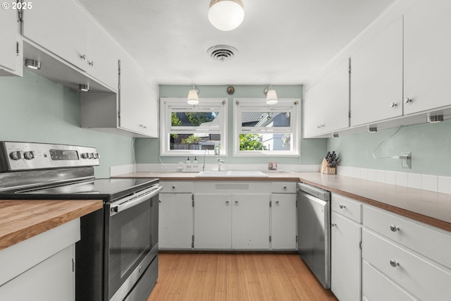 kitchen featuring appliances with stainless steel finishes, a sink, white cabinetry, and light wood-type flooring