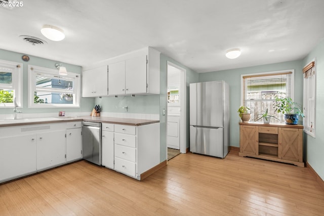 kitchen with appliances with stainless steel finishes, light wood-style floors, and white cabinets