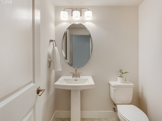 half bathroom with baseboards and toilet