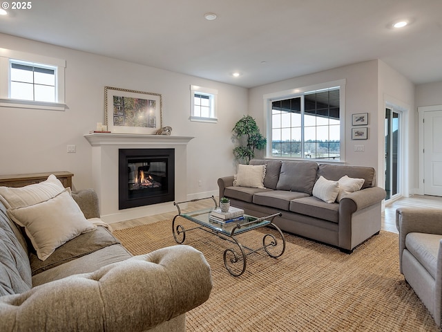 living room with baseboards, light wood-type flooring, a glass covered fireplace, and recessed lighting