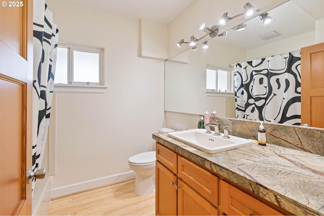 full bath featuring toilet, visible vents, baseboards, wood finished floors, and vanity