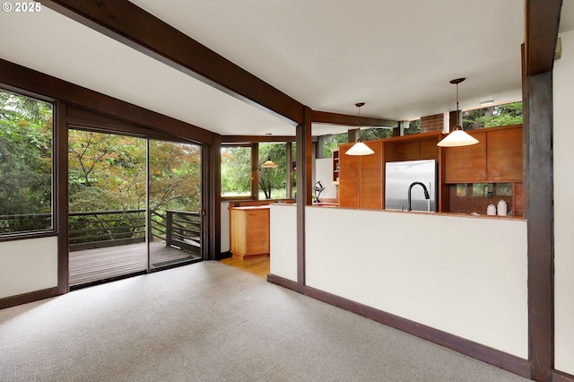 450 Horizon Rd, Eugene, OR 97405 - kitchen featuring stainless steel fridge, light colored carpet, brown cabinetry, hanging light fixtures, and healthy amount of natural light