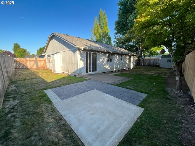 rear view of house featuring a fenced backyard, a storage unit, a lawn, and an outdoor structure