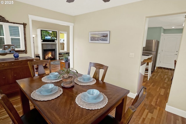 2146 NW Jetty Ave, Lincoln City, OR 97367 - dining room with wood finished floors, a tiled fireplace, baseboards, and a ceiling fan