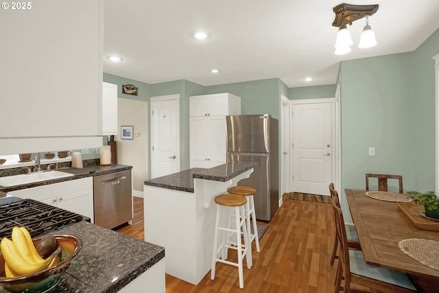 2146 NW Jetty Ave, Lincoln City, OR 97367 - kitchen with appliances with stainless steel finishes, a kitchen bar, white cabinets, light wood-style flooring, and recessed lighting