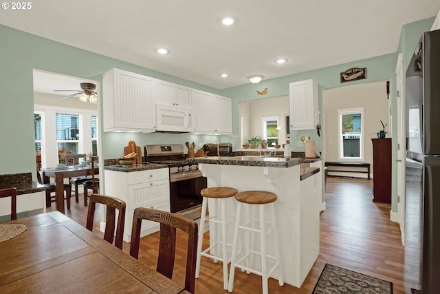 2146 NW Jetty Ave, Lincoln City, OR 97367 - kitchen with stainless steel appliances, a breakfast bar area, plenty of natural light, white cabinetry, and recessed lighting
