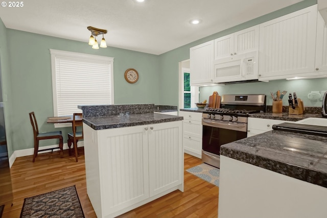 2146 NW Jetty Ave, Lincoln City, OR 97367 - kitchen with white microwave, stainless steel gas range, light wood-style flooring, a kitchen island, and dark countertops