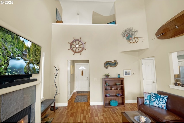 2146 NW Jetty Ave, Lincoln City, OR 97367 - living area featuring a high ceiling, a glass covered fireplace, light wood-style floors, and baseboards