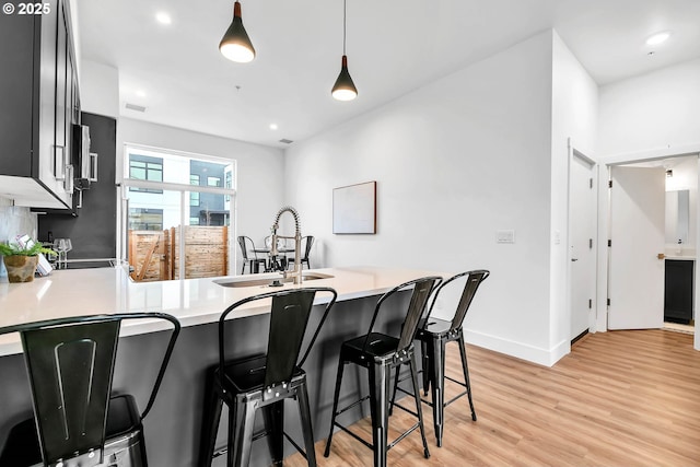 kitchen featuring kitchen peninsula, a kitchen bar, decorative light fixtures, and sink