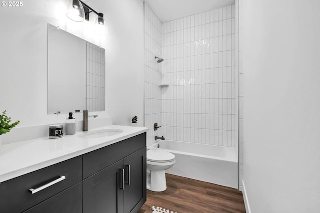 full bathroom with vanity, wood-type flooring, tiled shower / bath combo, and toilet