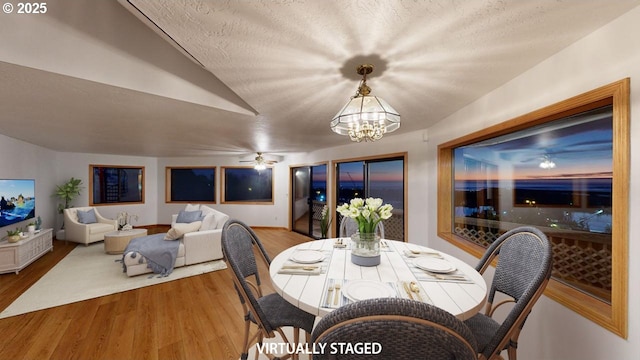 dining space featuring ceiling fan with notable chandelier, wood-type flooring, and a textured ceiling