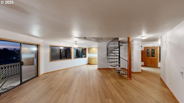 16151 Lower Harbor Rd, Brookings, OR 97415 - unfurnished living room with baseboards, stairway, a textured ceiling, and light wood finished floors