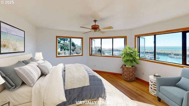 bedroom with a water view, ceiling fan, and light wood-type flooring