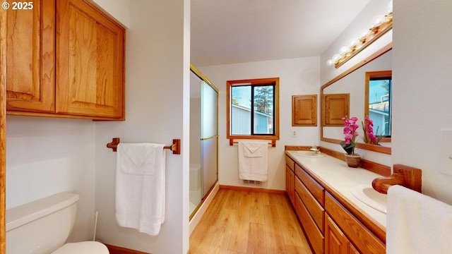 bathroom featuring hardwood / wood-style flooring, vanity, toilet, and a shower with shower door