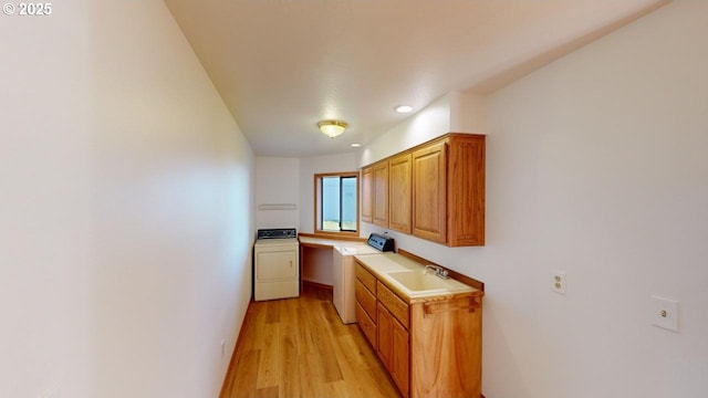 kitchen featuring washer / dryer, sink, built in desk, and light hardwood / wood-style flooring