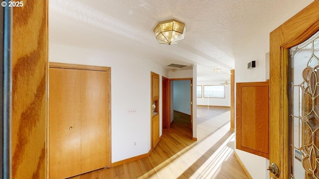 corridor featuring light hardwood / wood-style floors and a textured ceiling