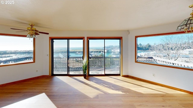 spare room with light hardwood / wood-style floors, ceiling fan, and a water view