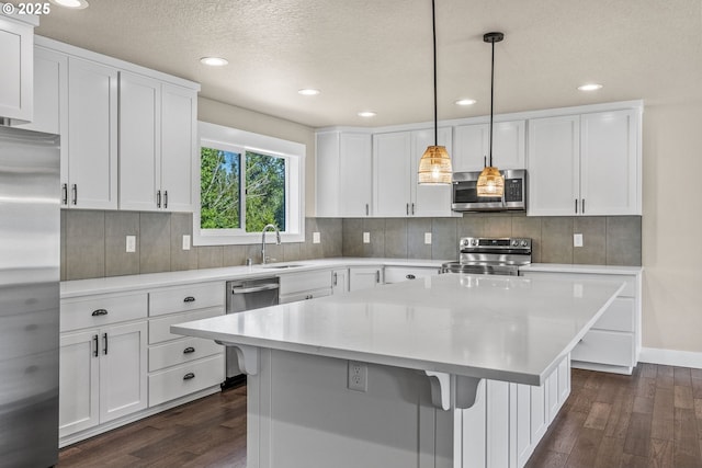 151 Alpha Dr, Longview, WA 98632 - kitchen featuring appliances with stainless steel finishes, dark wood-style floors, a sink, decorative backsplash, and white cabinets