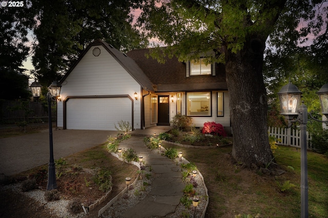 view of front of property with driveway, fence, an attached garage, and roof with shingles