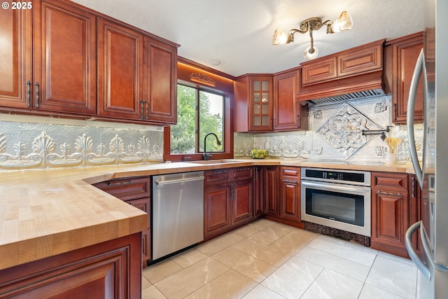 kitchen with stainless steel appliances, a sink, backsplash, and glass insert cabinets