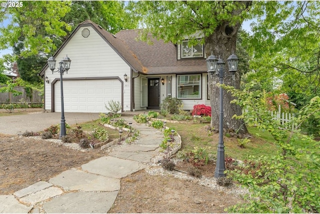 view of front of house with asphalt driveway, an attached garage, fence, and a shingled roof