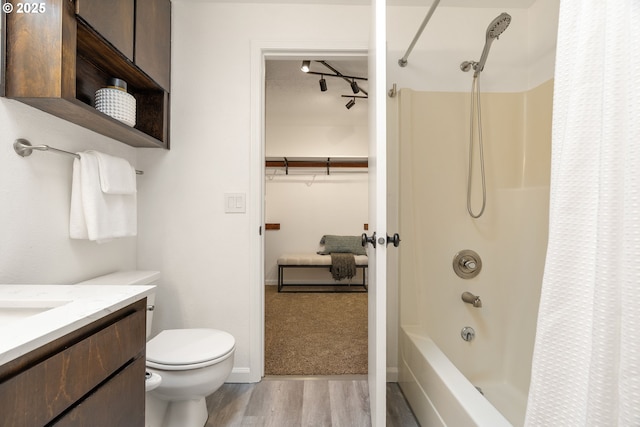 bathroom featuring wood finished floors, toilet, vanity, shower / bath combo with shower curtain, and rail lighting