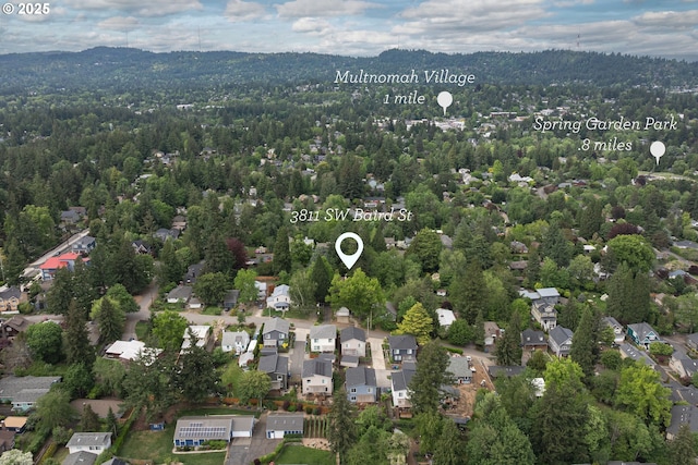 aerial view of property's location featuring a forest and nearby suburban area