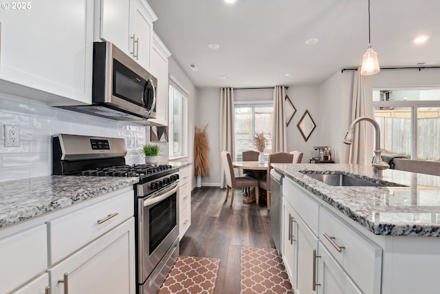 kitchen with backsplash, dark wood-style flooring, appliances with stainless steel finishes, and a sink