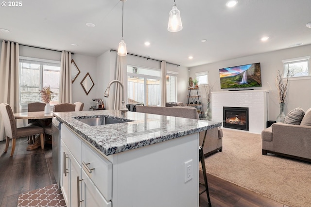 kitchen featuring a sink, dark wood-style floors, a glass covered fireplace, and white cabinets