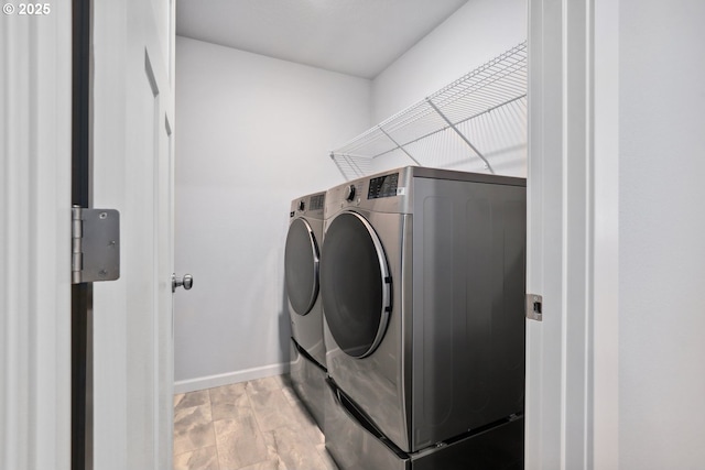 washroom with baseboards, washing machine and dryer, laundry area, and light wood finished floors