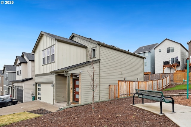 view of property exterior with a residential view, board and batten siding, a garage, and fence