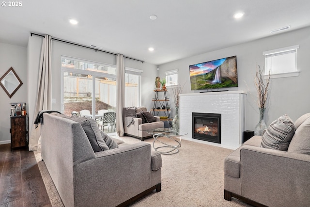 living room featuring recessed lighting, visible vents, a healthy amount of sunlight, and a glass covered fireplace