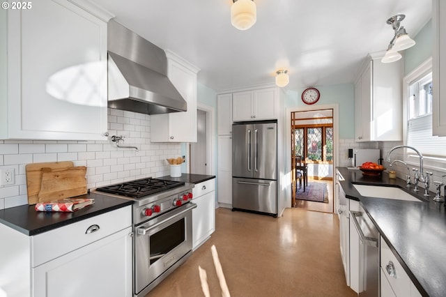 kitchen featuring dark countertops, white cabinetry, a sink, high quality appliances, and wall chimney exhaust hood